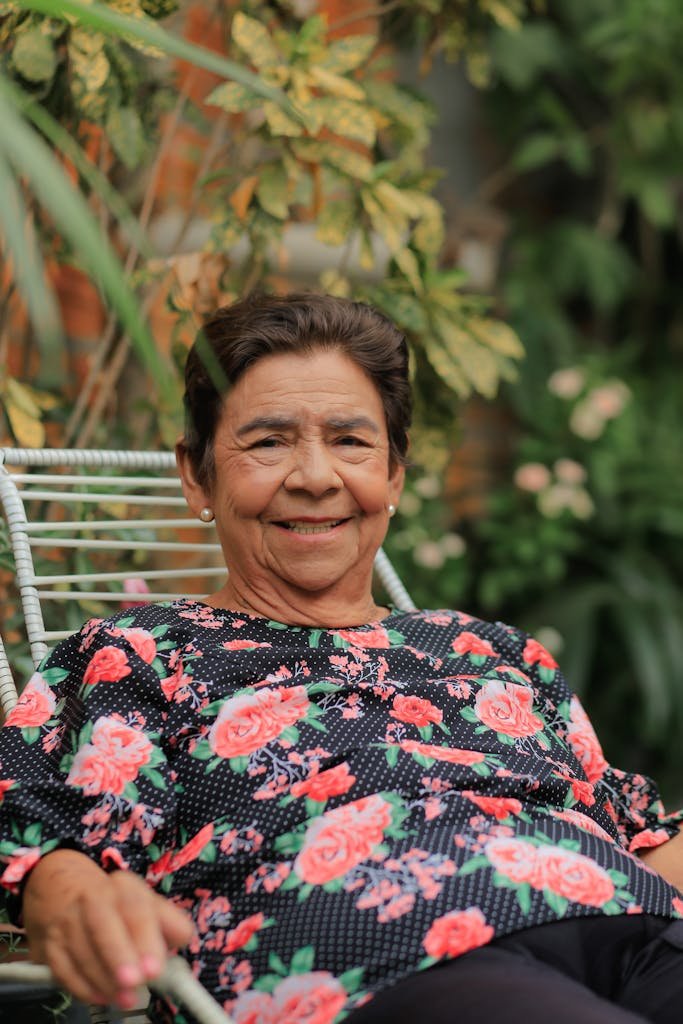 Elderly woman enjoying a peaceful moment outdoors in a garden setting.
